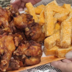 Golden crispy fried polenta slices served alongside crispy fried chicken wings on a rustic wooden platter, garnished with fresh parsley.